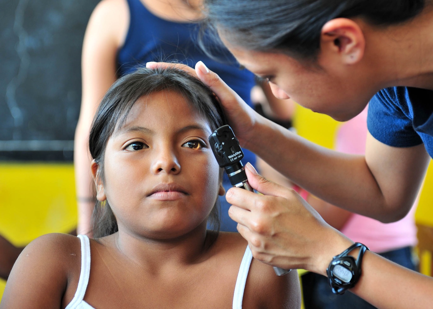 Examen ocular a una niña en una jornada de salud en Latinoamérica